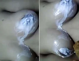 Pretty Indian girl wears a white dress while washing up in a stream.